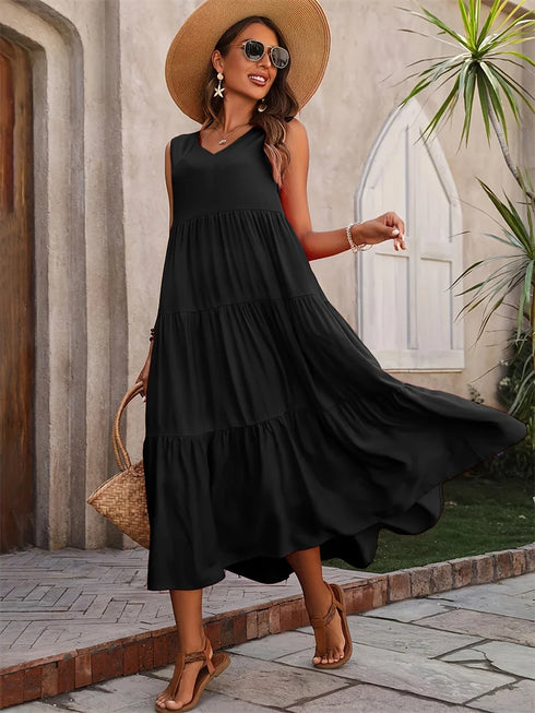 Woman in a black dress and straw hat standing outdoors.